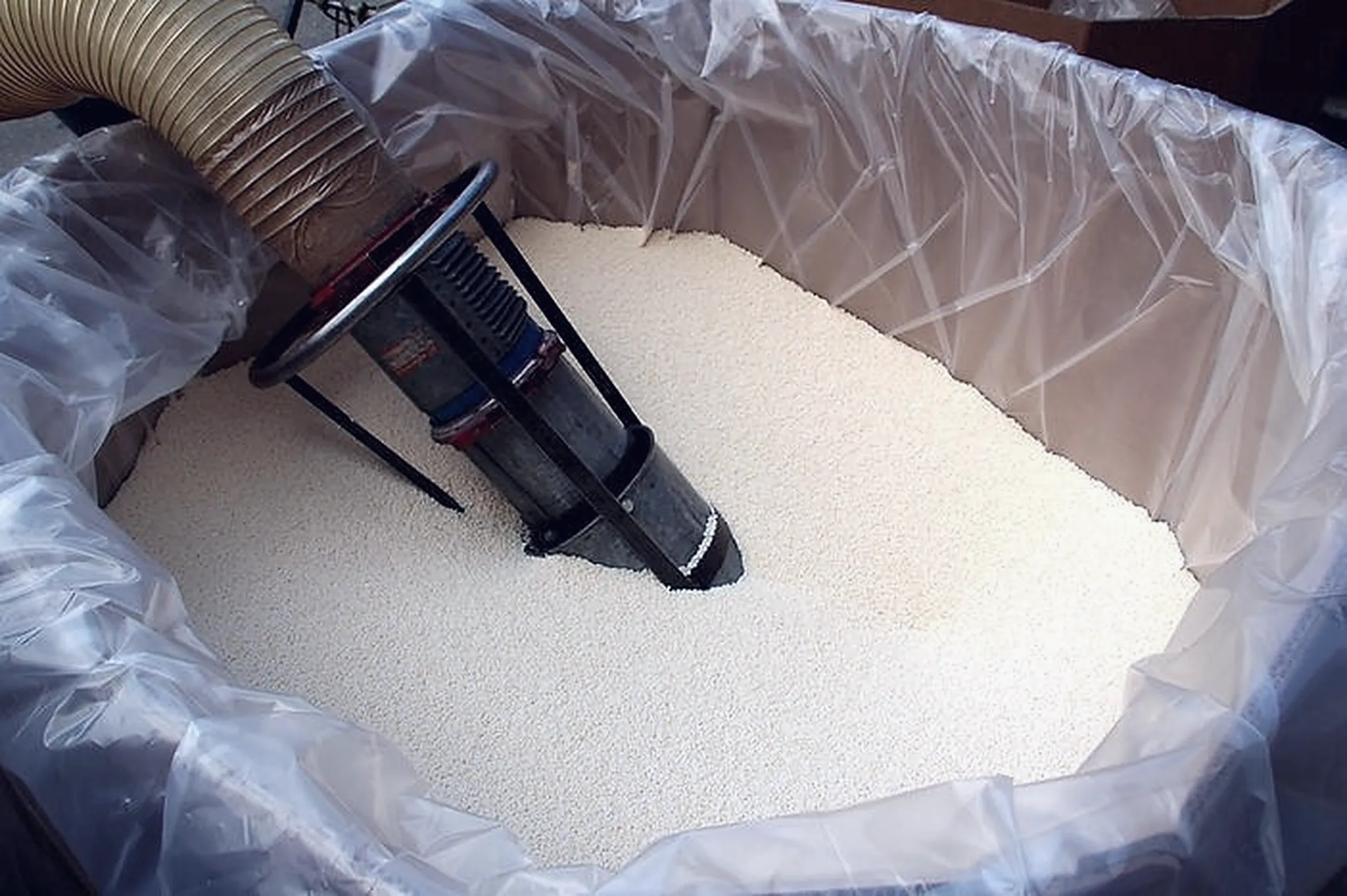 Pescante dell’aspiratore immerso nel granulo plastico bianco dentro un big bag