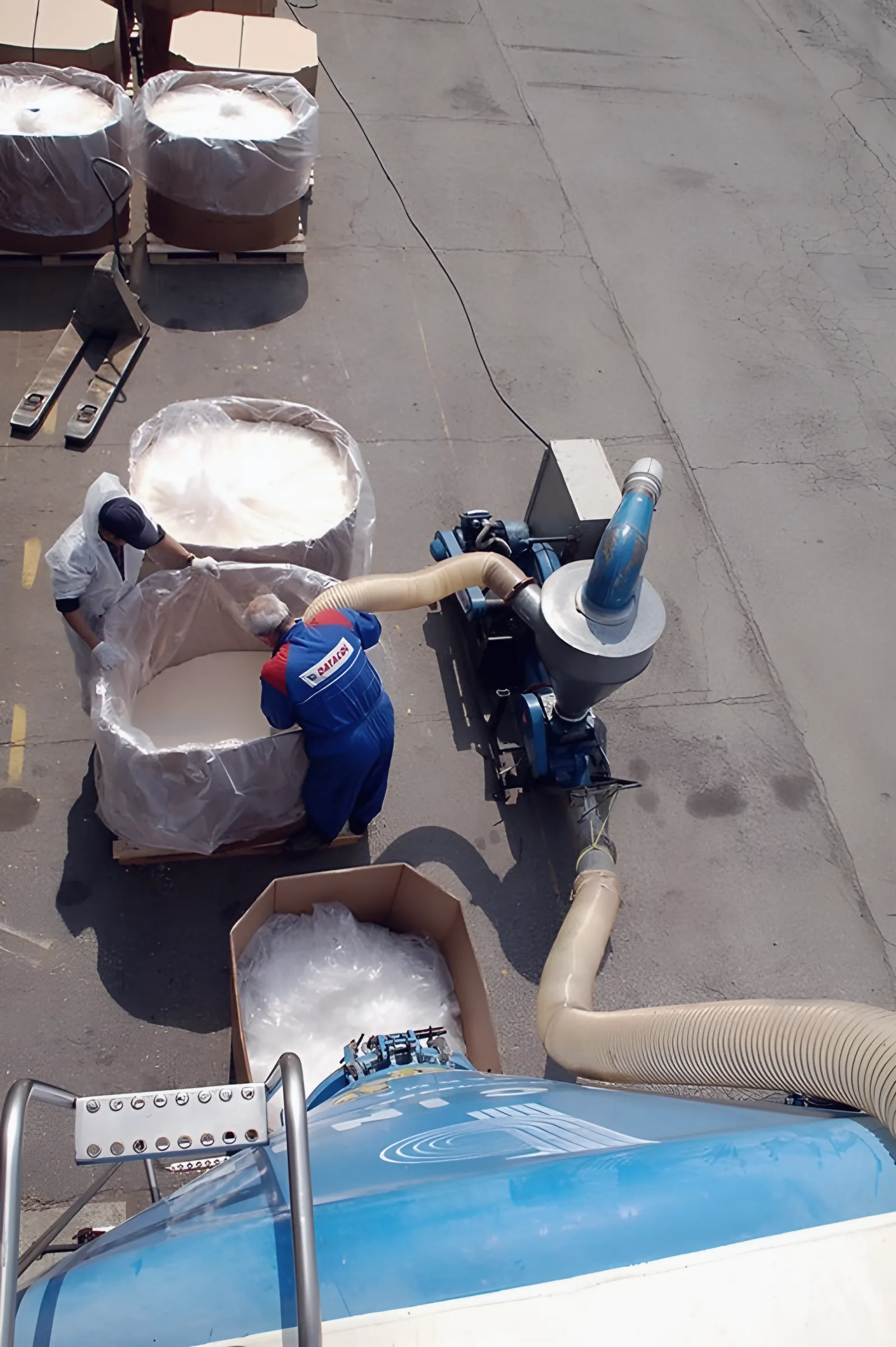 Operators vacuuming granules from open octabins with the mobile unit linked to a silo trailer