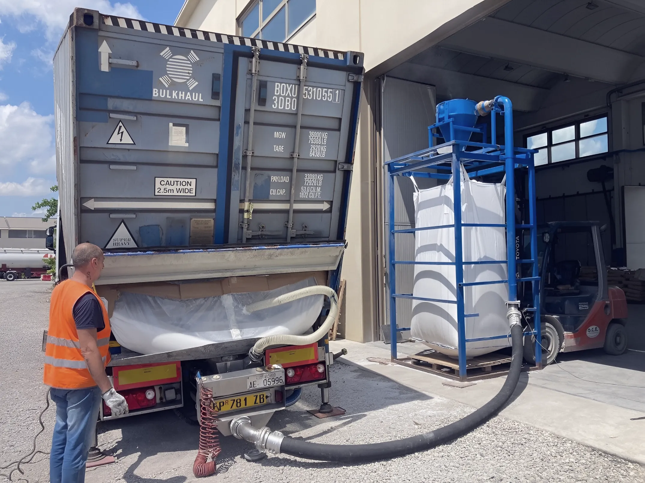 Operator emptying a lined bulk container into a big bag at a filling station