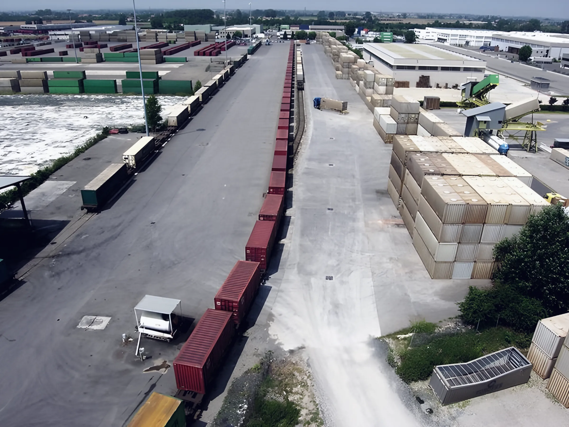 Aerial view of the depot: rail siding with wagons and red containers, stacked swap bodies and tippers