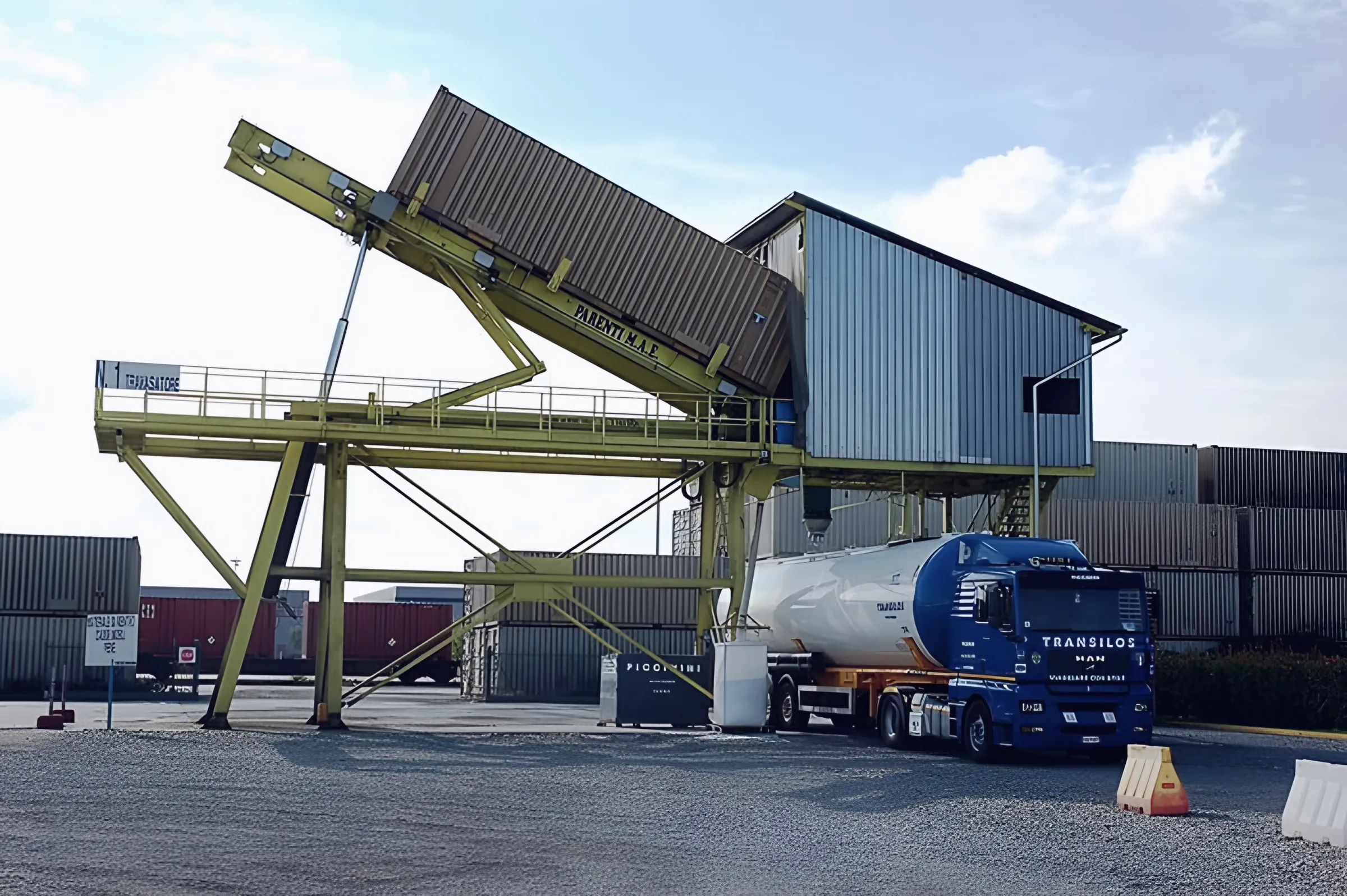 Travasatore giallo con container inclinato che svuota il materiale in un autosilos