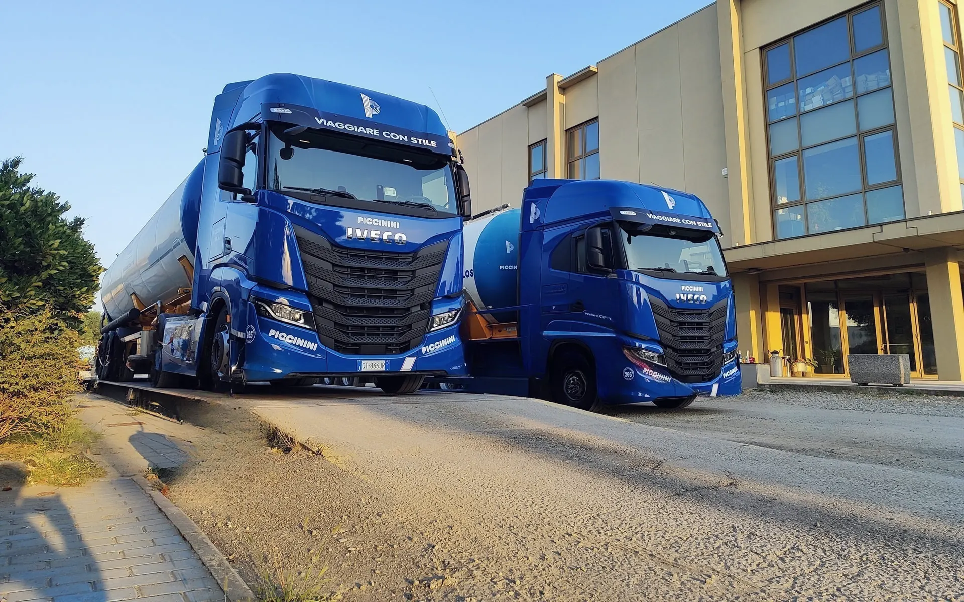 Due trattori stradali blu Piccinini con semirimorchi autosilos davanti alla sede all’Interporto di Parma
