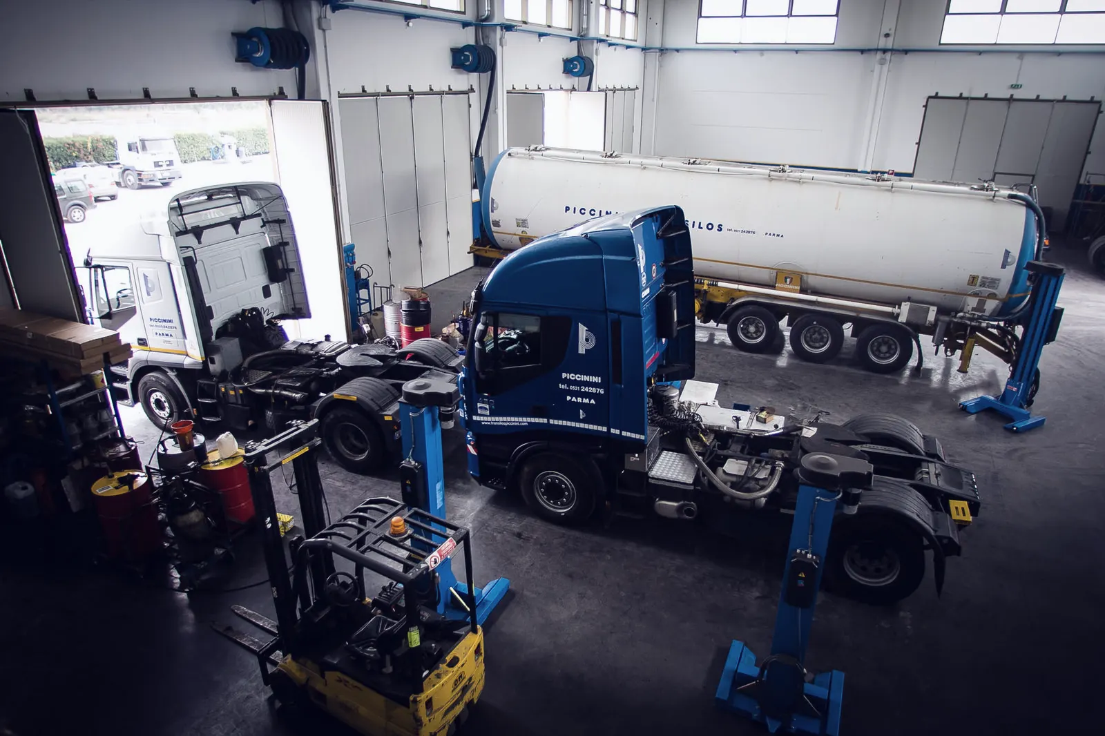 In-house workshop from above with two tractors under maintenance and a silo trailer