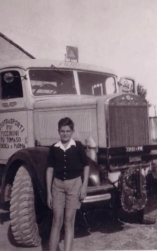 Boy in front of a lorry marked Autotrasporti F.lli Piccinini fu Tomaso, Fidenza e Parma